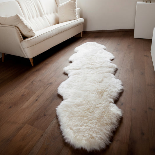 Schaffellteppich weiss vor weissen Sofa auf Holzboden